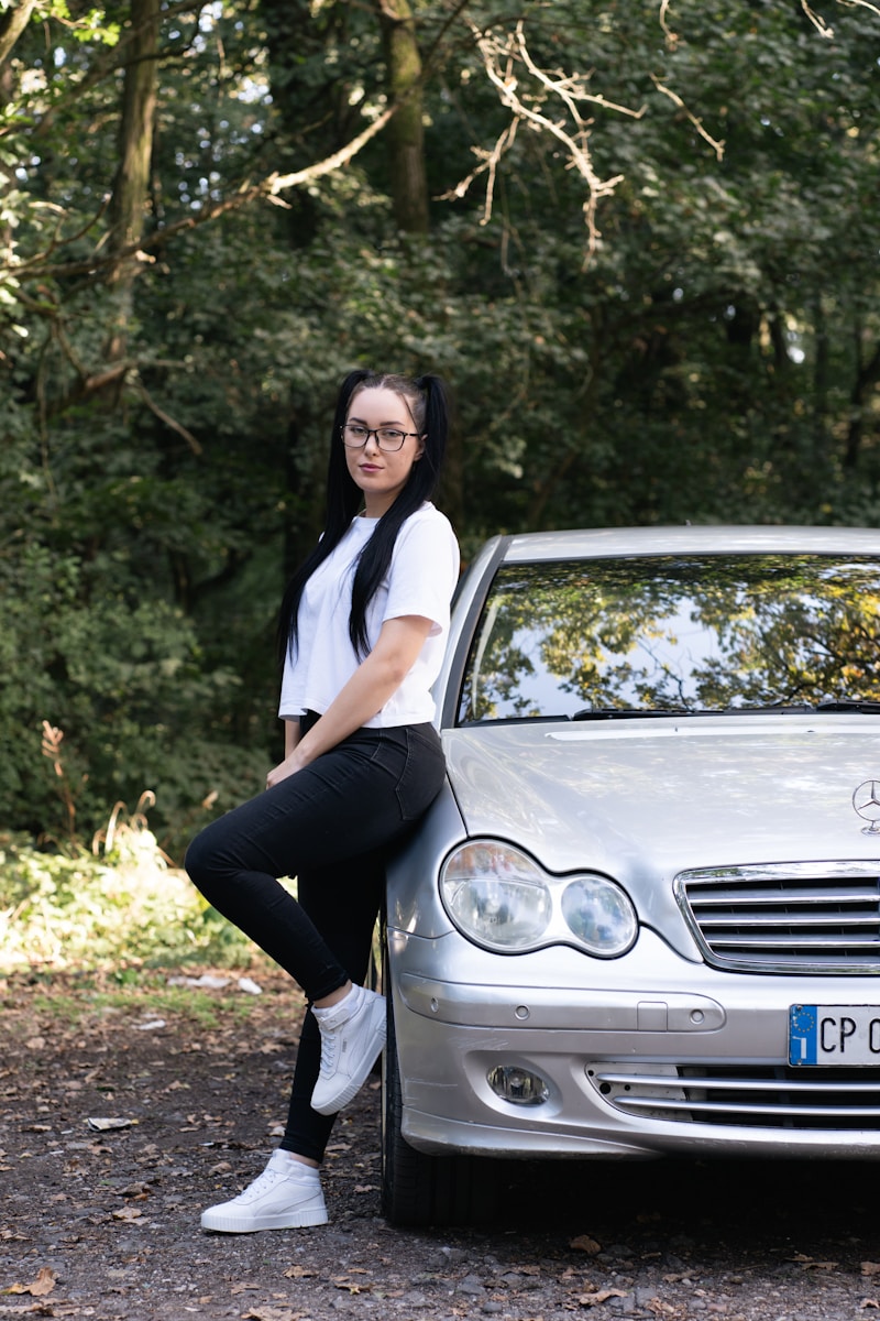 a woman sitting on the hood of a silver car with auto insurance